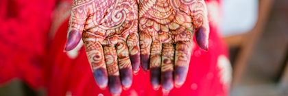 A person holds out their hands to show intricate henna designs on their palms.