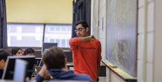 A graduate student looking out at the class of undergraduate physics students during a lab.