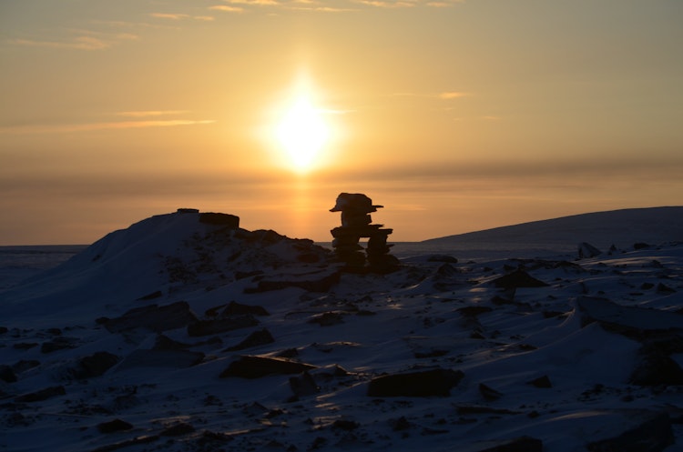 An Inuksuk silhouetted at sunset