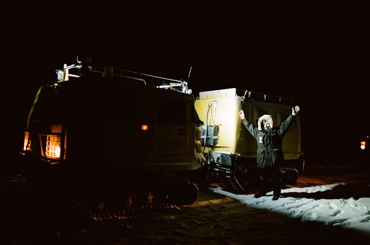 Michelle, outside of the Alert station at night, with arms raised in celebration
