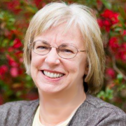 Headshot of Mary Visser Kerr in front of red flowers