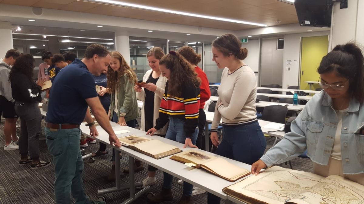Students view and touch several historical texts from the University of Guelph archives, including an atlas.