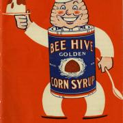 Red cookbook cover with a cartoon character with a bee hive head advertising corn syrup.