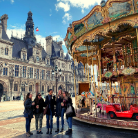 Students walk by a French hotel and carousel