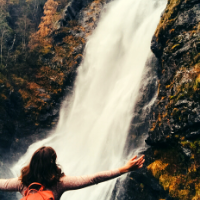 Student stands in front of a waterfall in Norway