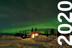 Small cabin in the snowy forest with the Norther Lights in the sky