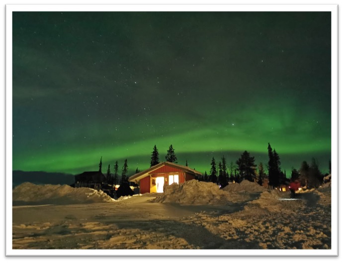 Snow covered house in Sweden with Northern Lights in sky