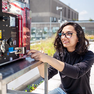 female student using a device on a rooftop lab