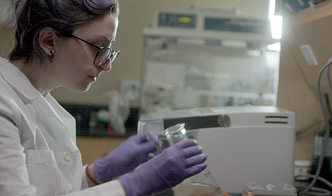 Woman in white lab coat holding a beaker