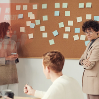 people working putting sticky notes on a board