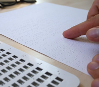 person's finger using braile