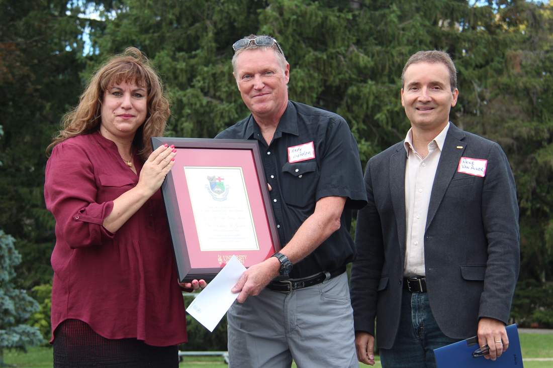 Anna DeMarchi-Meyers, Andy Gordon and Rene Van Acker pose outside with framed certificate