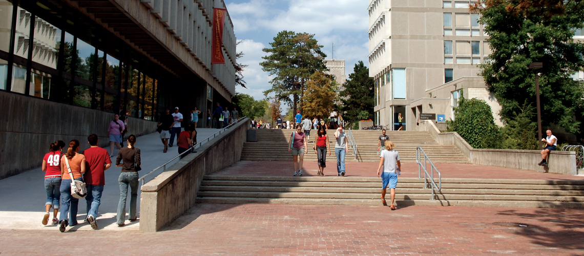 Many students walking on red brick walkway with stairs