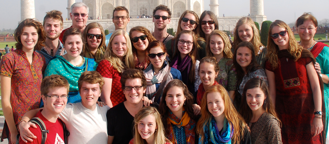 Group of students and professors stand together in front of the Taj Mahal in India