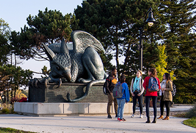 Group of five students talking in front of the Gryphon statue