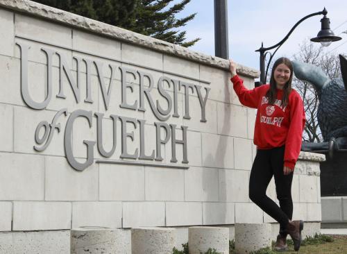 Student in front of University of Guelph stone wall