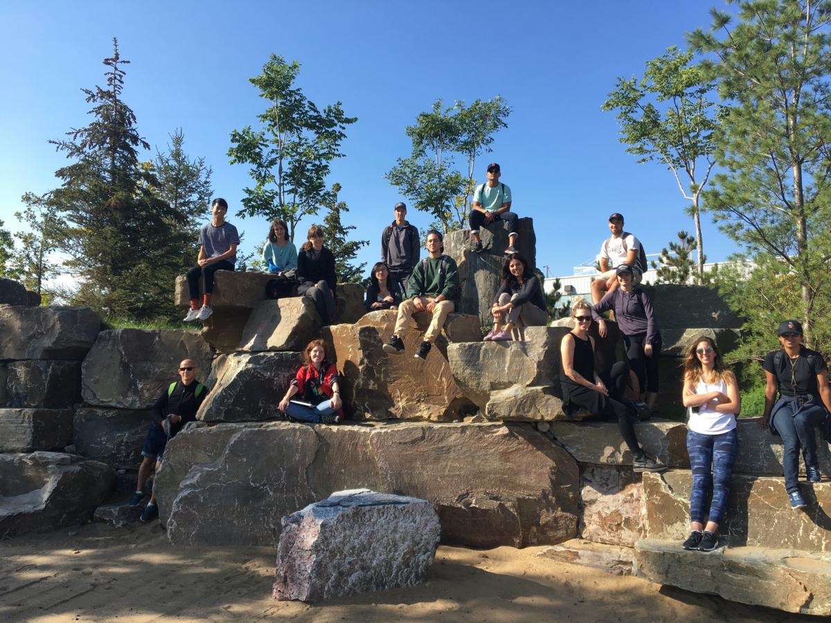 Students standing and sitting on rocks