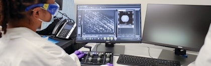 person in lab viewing microscopic image on computer screen