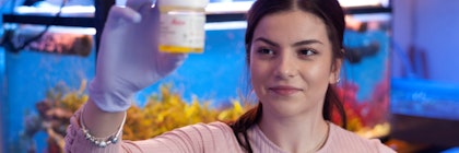person in front of aquarium holding sample