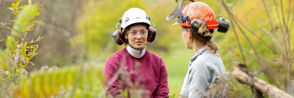 two people talking in nature wearing hard hats