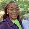 Annia smiles with green swamp in background holding papers