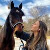 Grace holds lead of large brown horse and pets nose