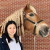 Anna smiles with large brown horse with a braided mane