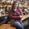 Bachelor of Commerce Student, Yuha Khan, sits in front of a large group of students in a lecture hall.