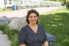 Dr. Monica Cojocaru sitting on a rock on campus, smiling.