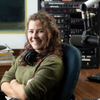 Maaike sits in a recording studio wearing over-ear headphones around her neck and smiling.