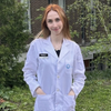 Bio-med graduate Rebecca Romanishen standing outside, wearing a lab coat with her hands in her pockets.