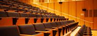 Image of arts research centre auditorium with rowed seating, wood paneled walls and warm lighting