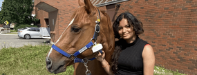 anushka standing outside next to a horse