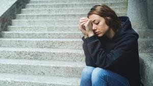 Student sitting on ground looking distraught