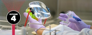 Close-up of a lab technician’s nitrile-gloved hands holding a petri dish behind a rectangular mounted magnifying glass