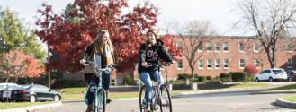 2 students biking on campus