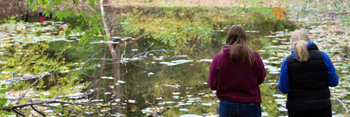 Two students standing next to a pond