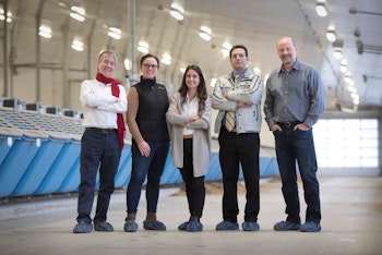 The Research Team pose for a photo standing in a large dairy barn.