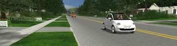 Virtual reality-generated image from the SafePeds platform showing a white car driving down a residential street, with houses and sidewalks visible in the background.