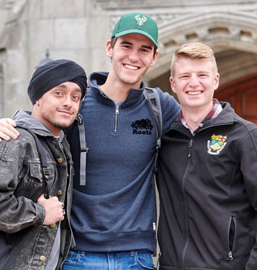 Three male students stand together smiling