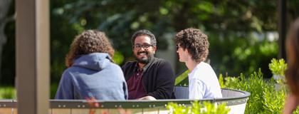Three business students sitting in Lang Plaza on a bench.