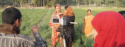 Videographers stand in field with farmers