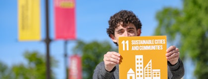 Image of a student holding a sign that reads '11 Sustainable Cities and Development'