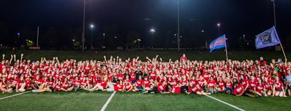 Orientation Volunteers (OVs) in a group on the football field after Pep Rally