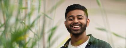 Picture of a student smiling in a field of grass.