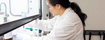Female student in a lab, pipetting a solution from a beaker