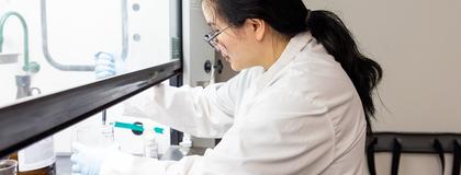 Female student in a lab, pipetting a solution from a beaker