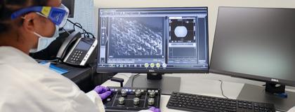 person in lab viewing microscopic image on computer screen