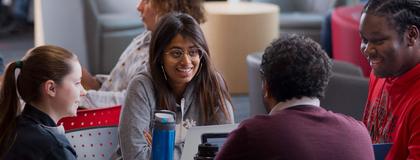 a group of diverse students sitting at a table and chatting