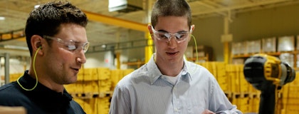 Two engineers wearing protective goggles working in a warehouse